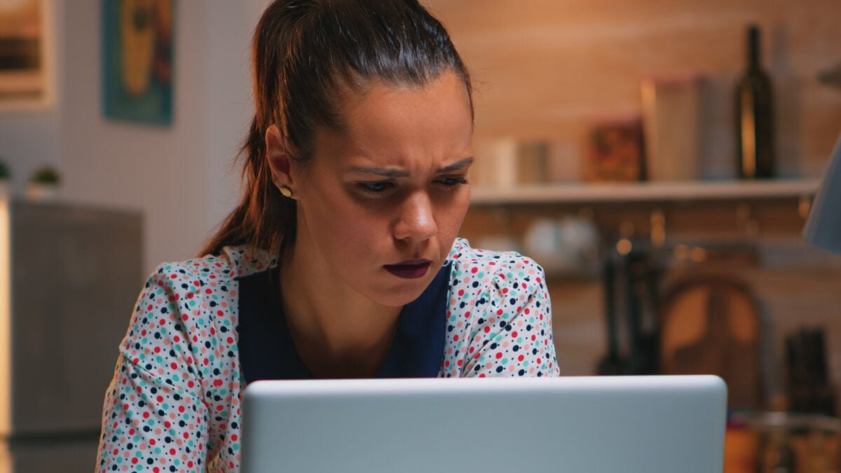 tired freelancer squinting while reading emails working from kitchen home late night front laptop bu